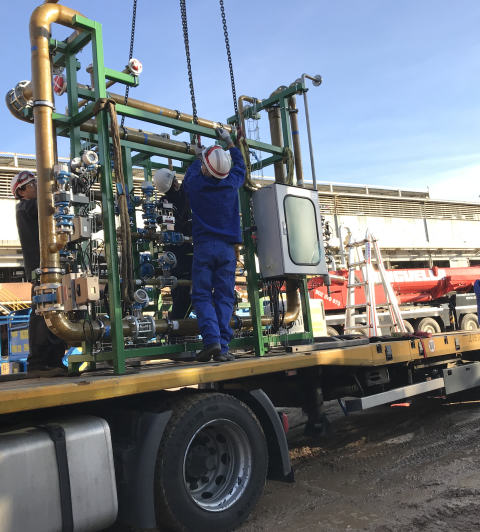 Zwei Arbeiter in blauen Overalls installieren Industrieanlagen auf einem LKW.