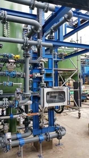 Komplexes industrielles Rohrleitungssystem mit blauen Stützen, grauen Rohren und einem weißen Steuerkasten.