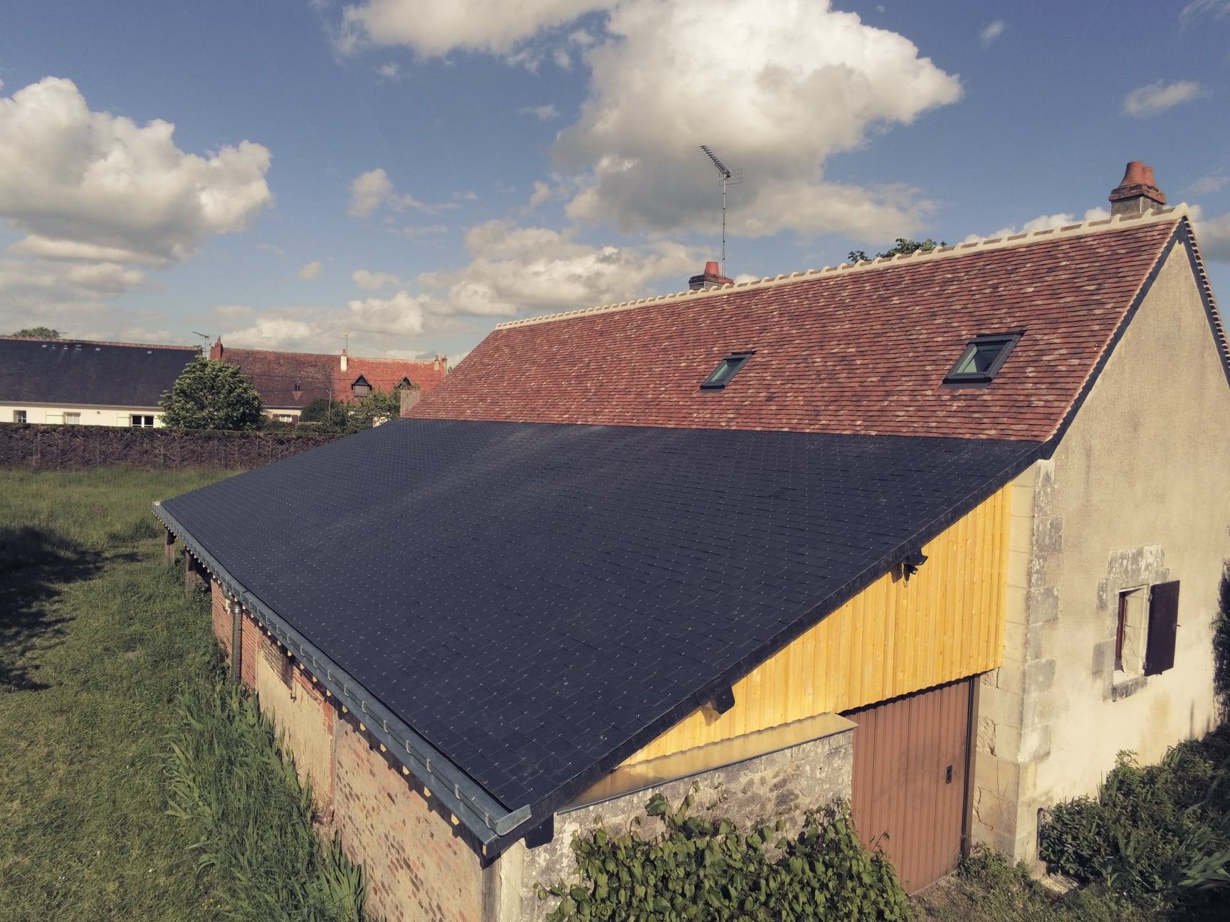 Une maison avec toiture en tuiles et ardoises