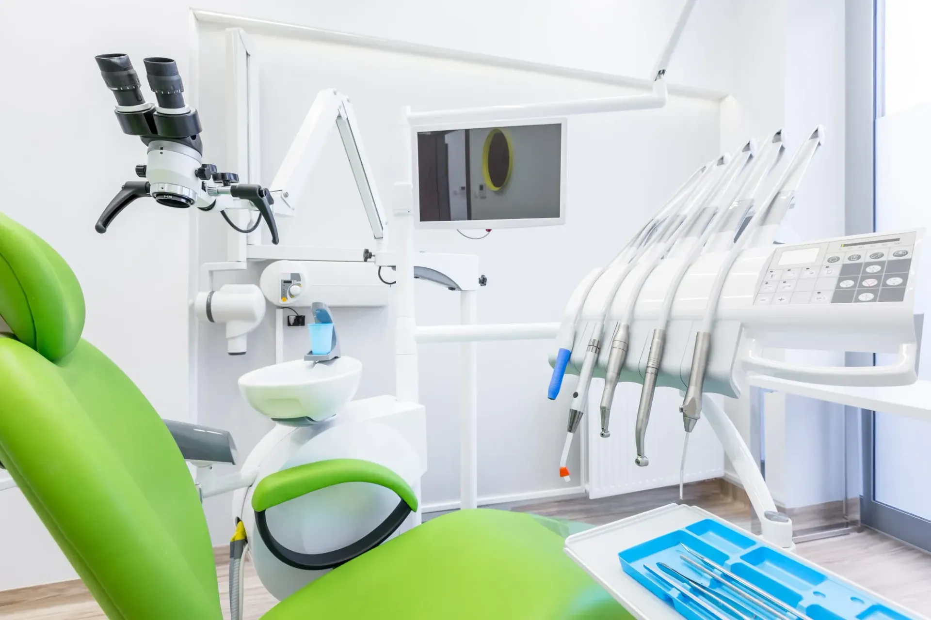 Una sala de exploración dental luminosa y moderna, equipada con un sillón de color verde lima