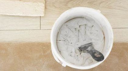 Un cubo blanco lleno de pintura blanca y una espátula.