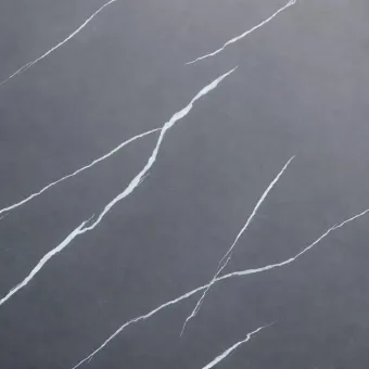 Superficie de piedra gris oscuro con vetas blancas sutiles, finas e irregulares que recorren su textura.