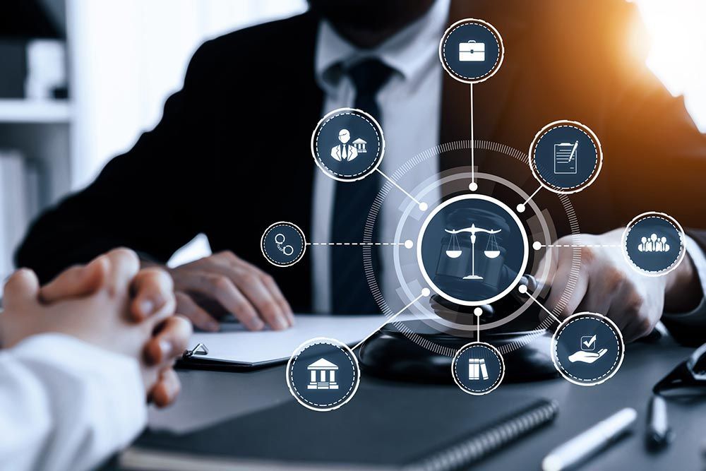 Reunión de negocios con manos sobre una tableta e iconos legales digitales en la pantalla.