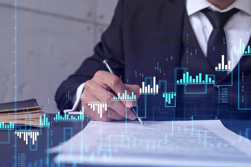 Empresario firmando documentos con un gráfico financiero azul superpuesto sobre un escritorio.