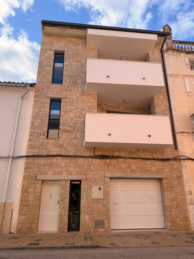 Un edificio estrecho de piedra de tres plantas con garaje, puerta 