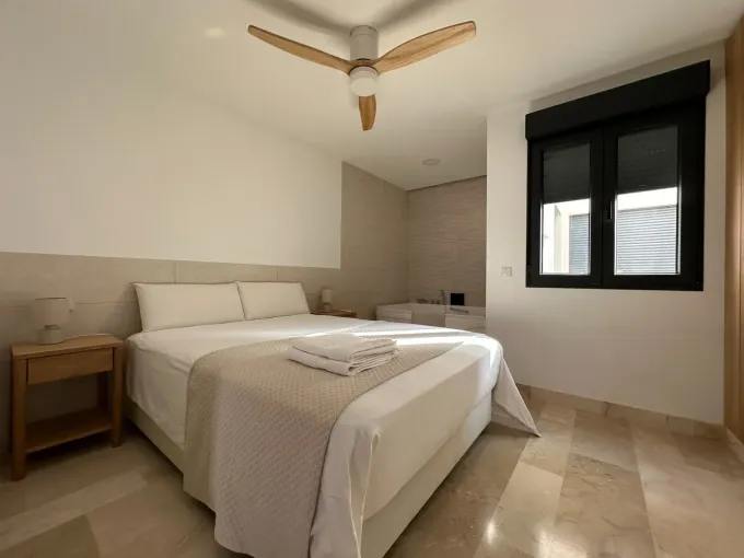 Un dormitorio luminoso con una cama de matrimonio con