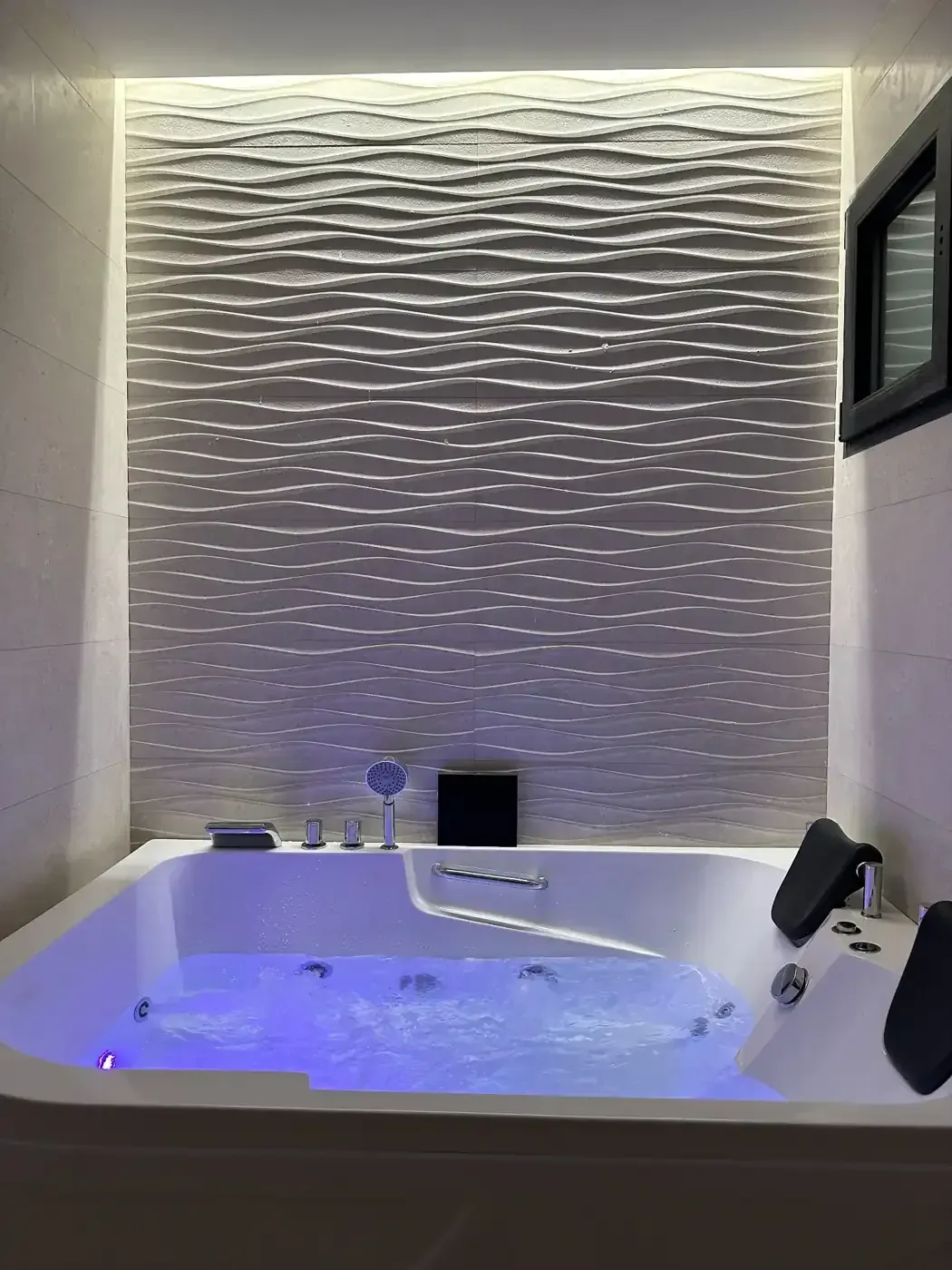 Una bañera de hidromasaje blanca con agua azul brillante, colocada contra una pared