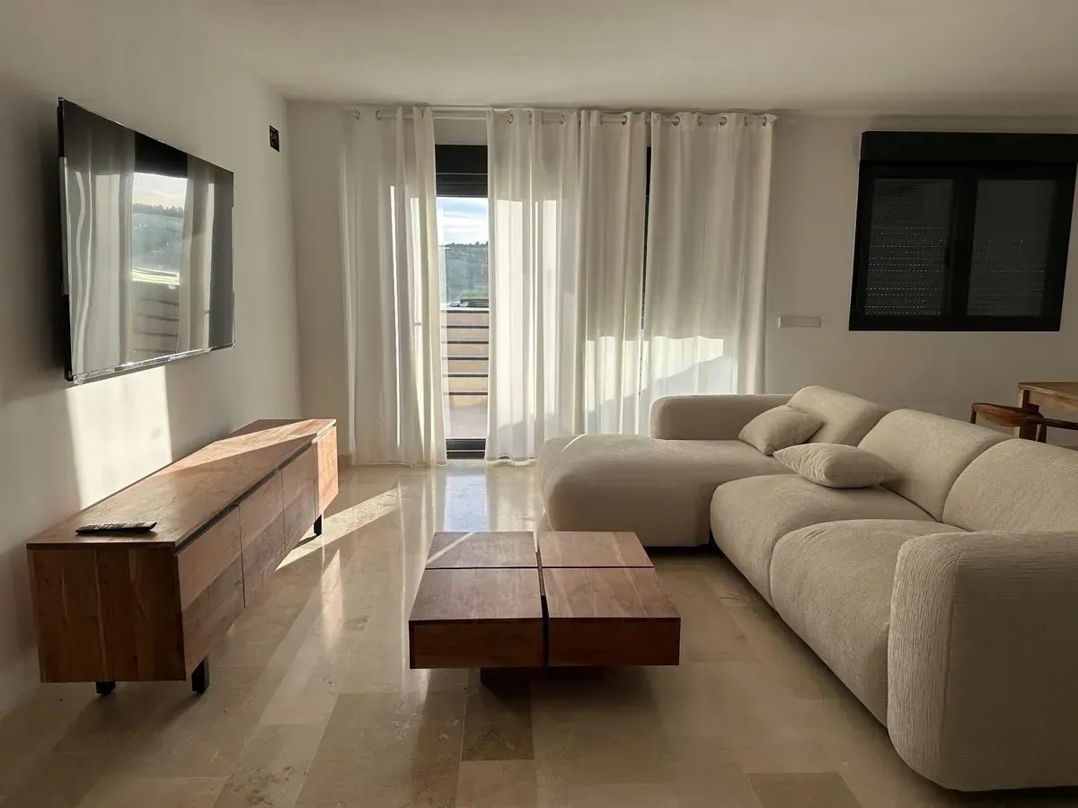 Un salón moderno y minimalista con un sofá modular beige, una