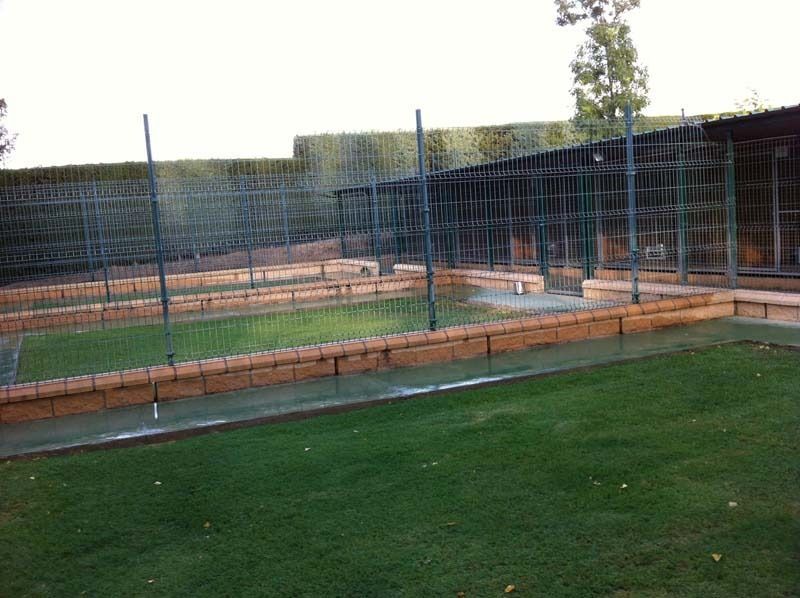Un campo de fútbol con una valla alrededor y un muro de ladrillos.