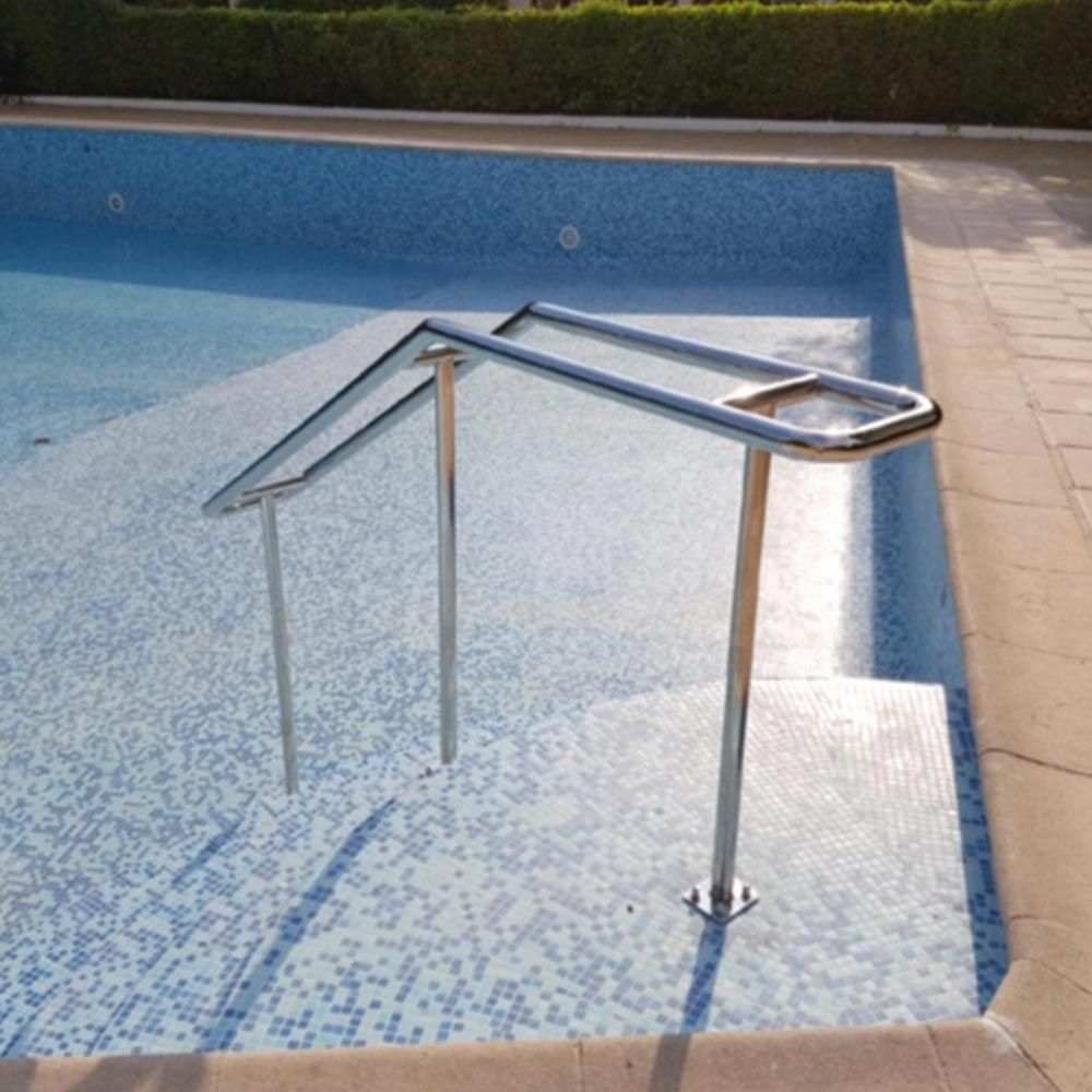 Rambarde de piscine en métal avec marches donnant sur une piscine bleue, à côté d'une terrasse carrelée.