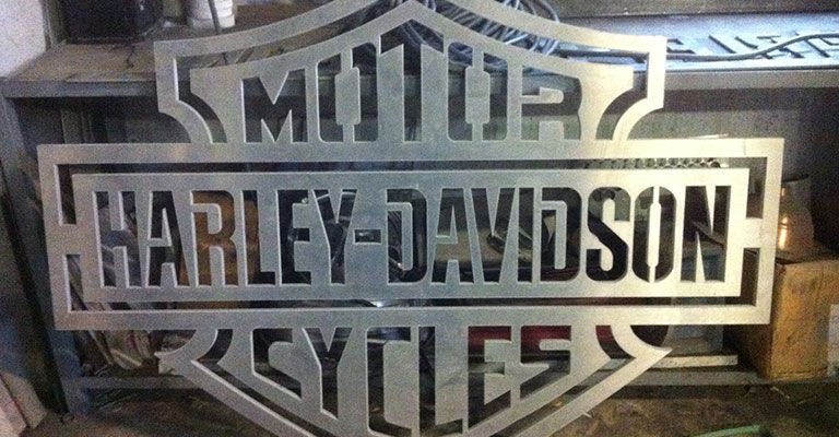Logo Harley-Davidson Motorcycles sur une plaque métallique avec lettrage noir et argent.