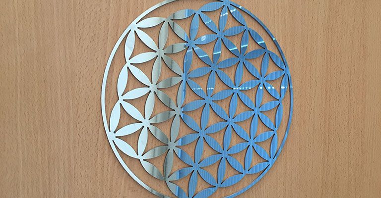 Plaque ronde géométrique bleue en forme de fleur de vie sur une surface en bois