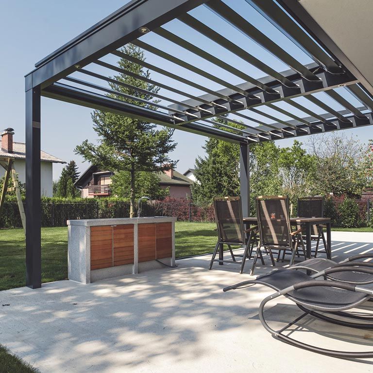 Terrasse moderne dans le jardin avec une pergola noire, une table à manger, des chaises et un barbecue intégré sous les arbres