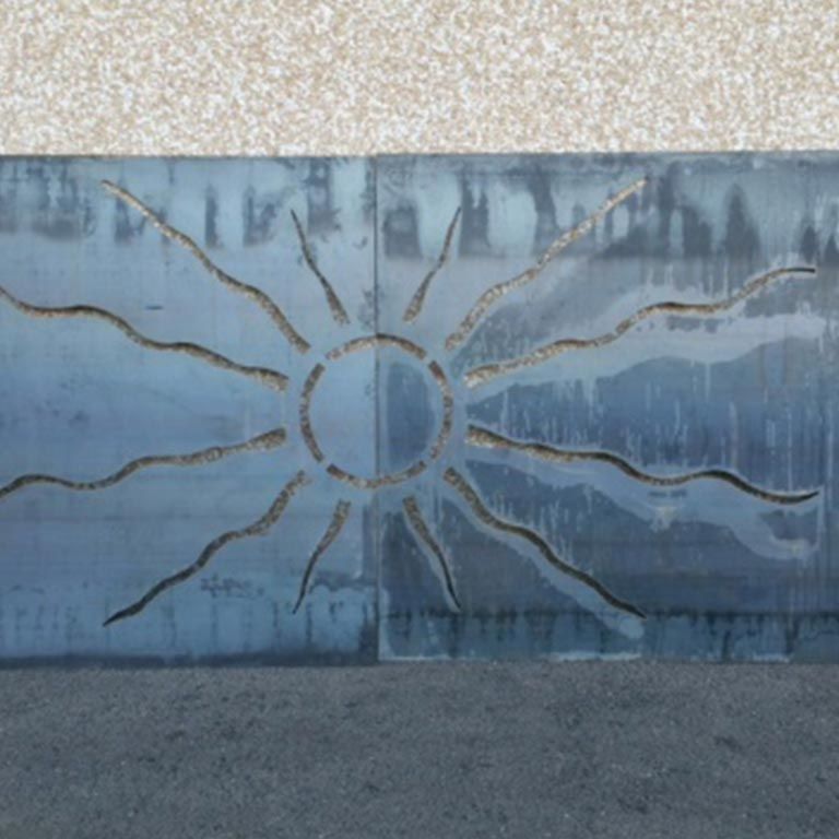 Fresque murale bleue avec un motif de soleil rayonnant au centre et un pavé sombre au premier plan.