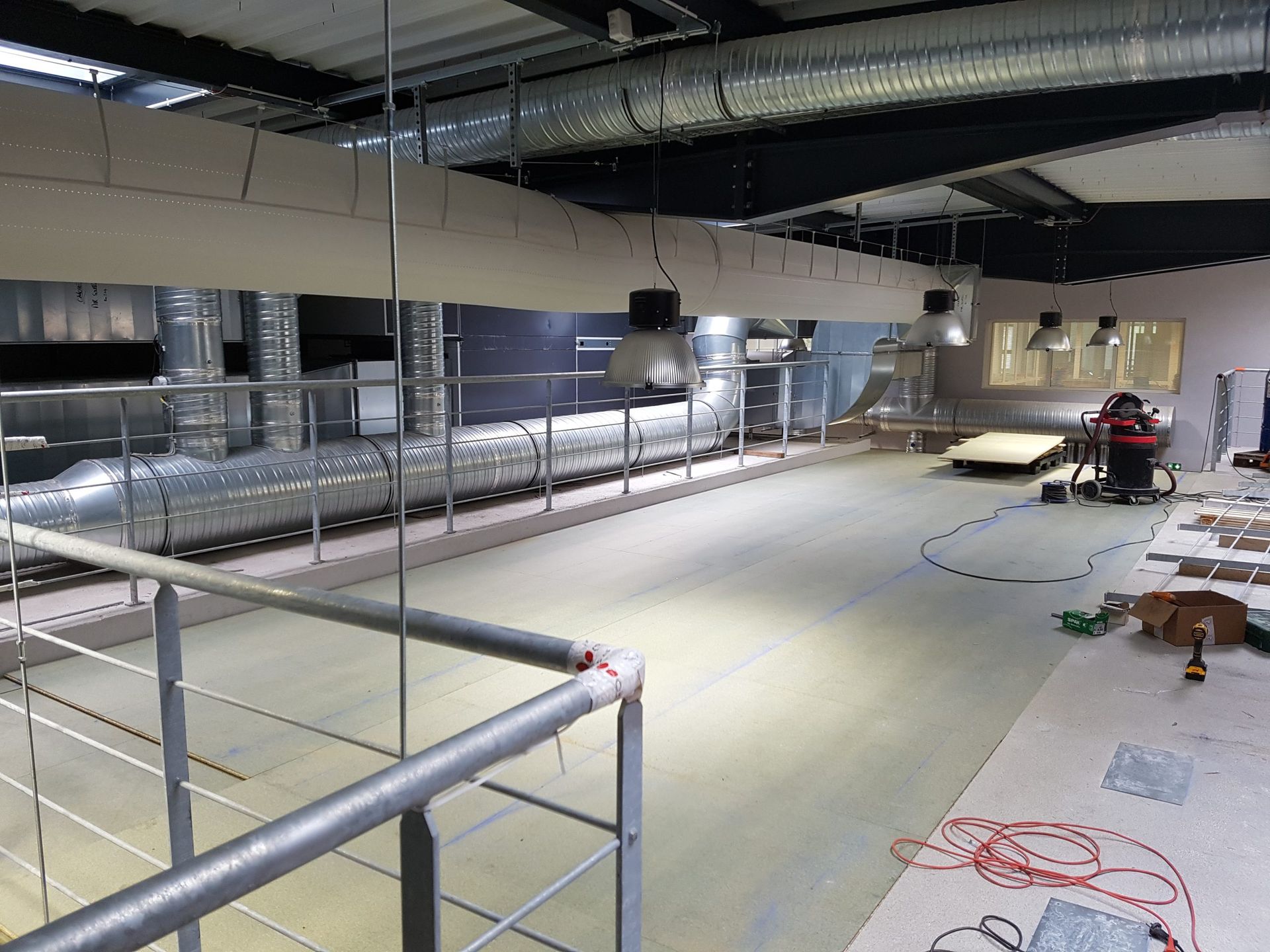 Intérieur industriel avec plafond apparent, balustrades et un grand espace ouvert en construction