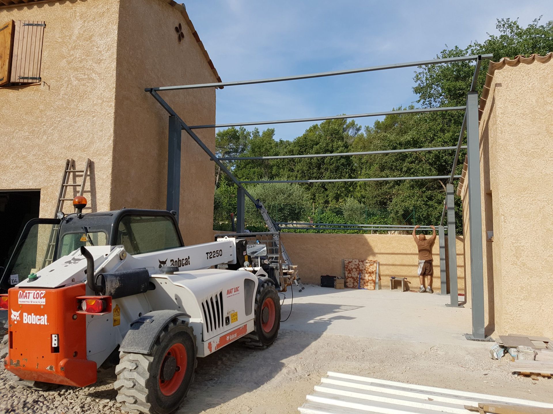 Chargeuse de chantier dans une cour à côté de bâtiments beiges et de matériaux empilés