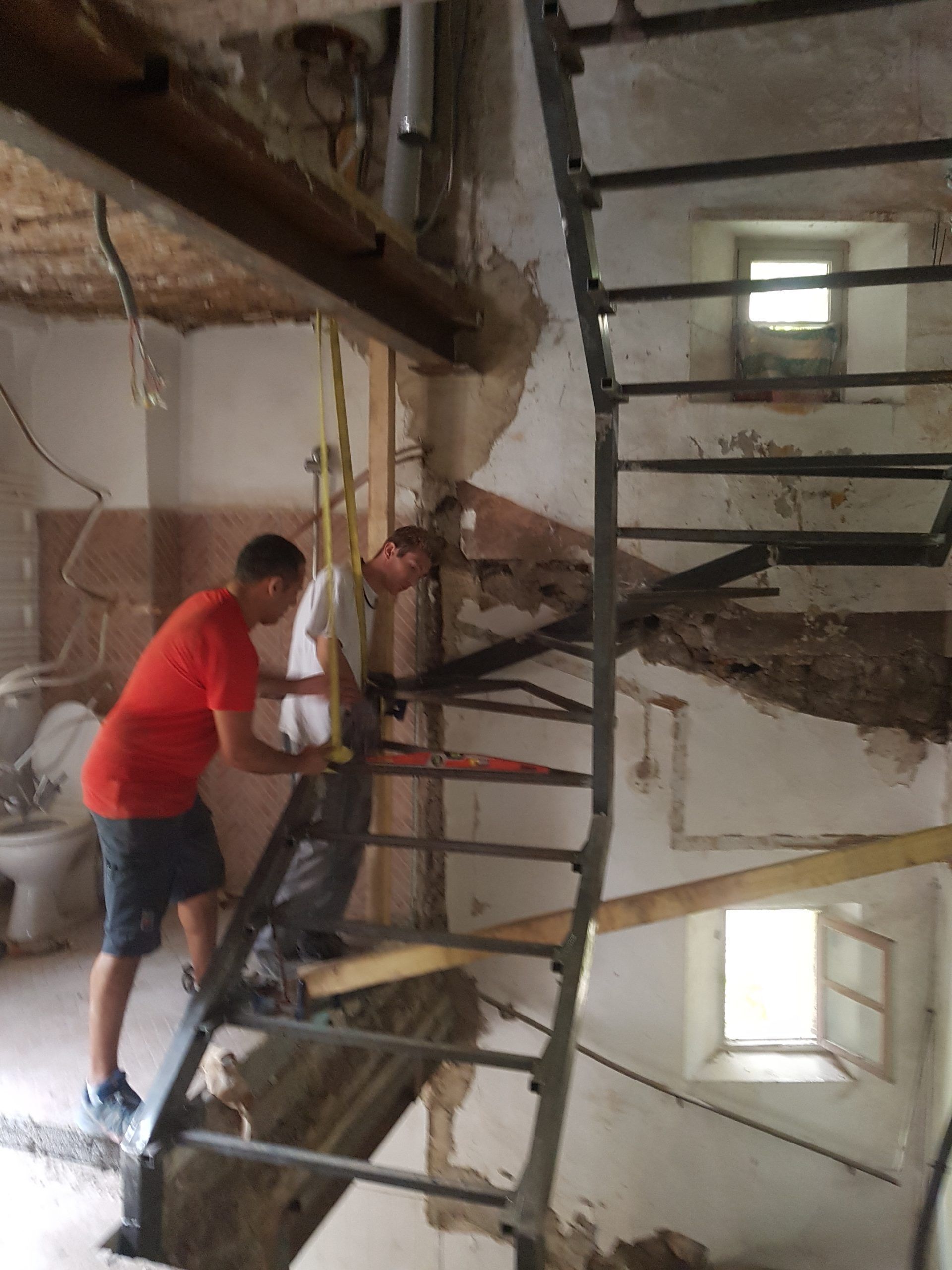 Deux ouvriers transportent une échelle dans une cage d'escalier étroite d'un bâtiment endommagé