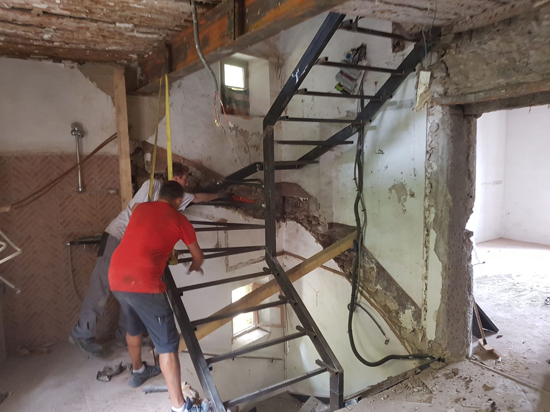 Deux personnes démolissent un mur intérieur endommagé à l'aide d'un escalier métallique à l'intérieur d'un bâtiment ravagé par les flammes.