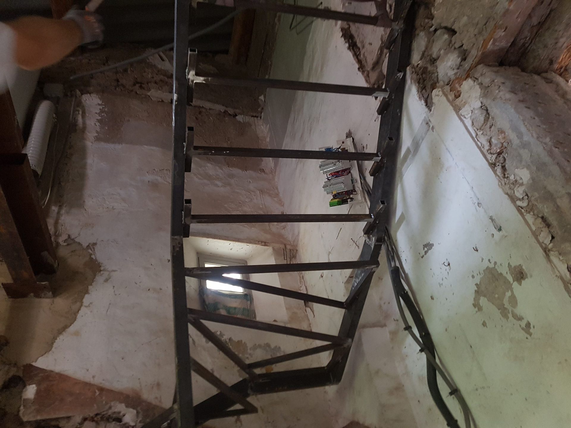 Escalier délabré dans un couloir étroit et abîmé, aux murs décrépis et aux poutres en bois apparentes.