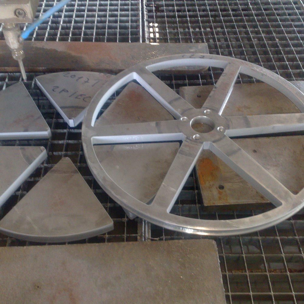 Des pièces métalliques et des disques en forme de roue sur une surface en treillis métallique, dont une grande roue argentée à cinq rayons.