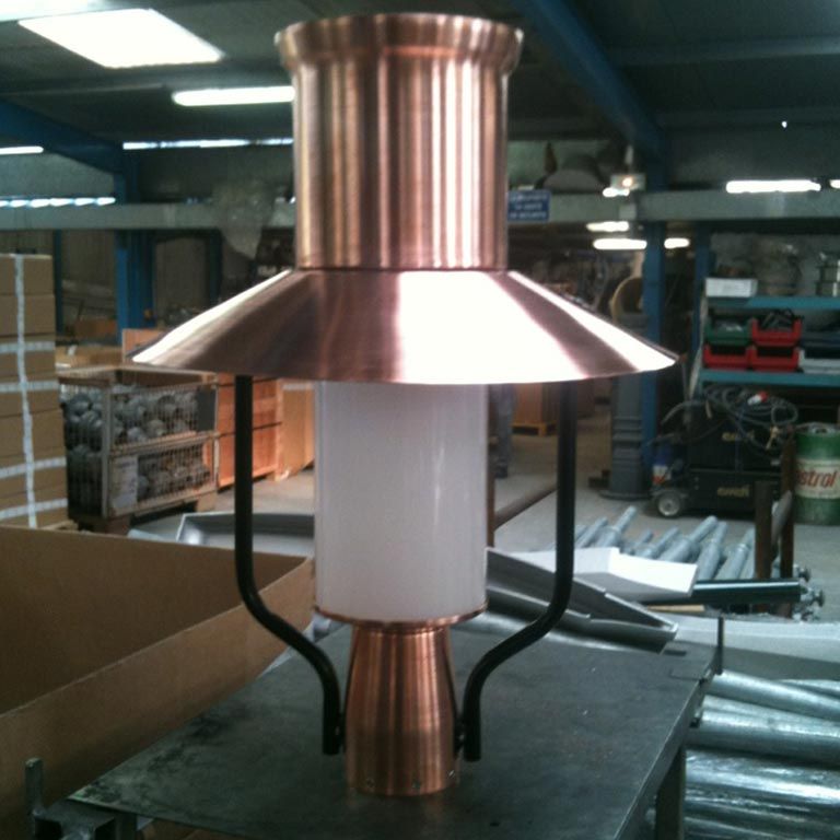 Prototype de lampe industrielle couleur cuivre avec un centre cylindrique blanc dans un atelier