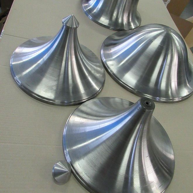 Des pièces coniques en métal argenté brillant, aux bords cannelés, disposées sur une table