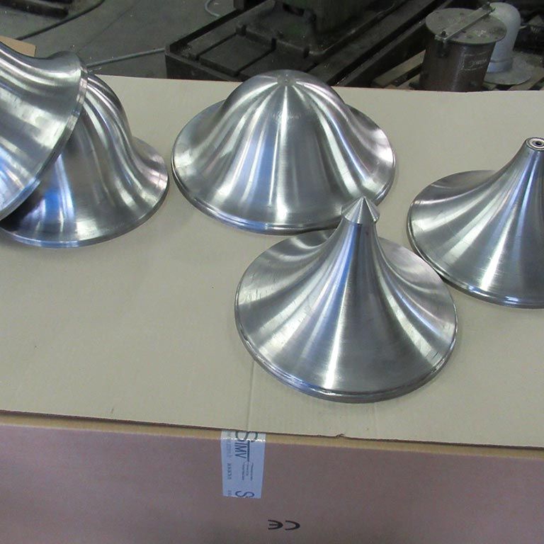 Quatre cônes métalliques brillants sur une boîte en carton dans un atelier