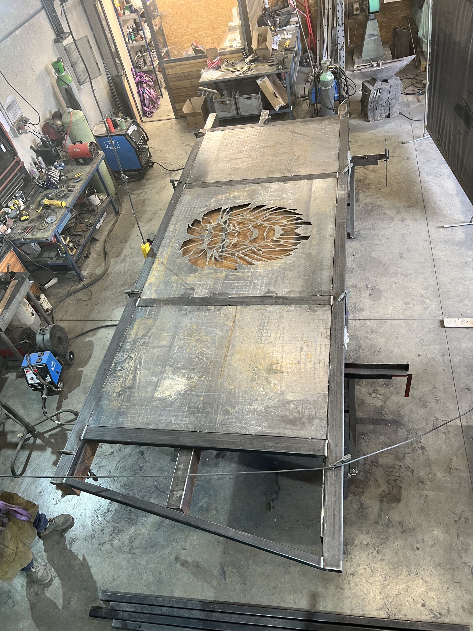 Plateforme métallique rouillée dans un atelier industriel, vue de dessus, avec des outils et des débris éparpillés.