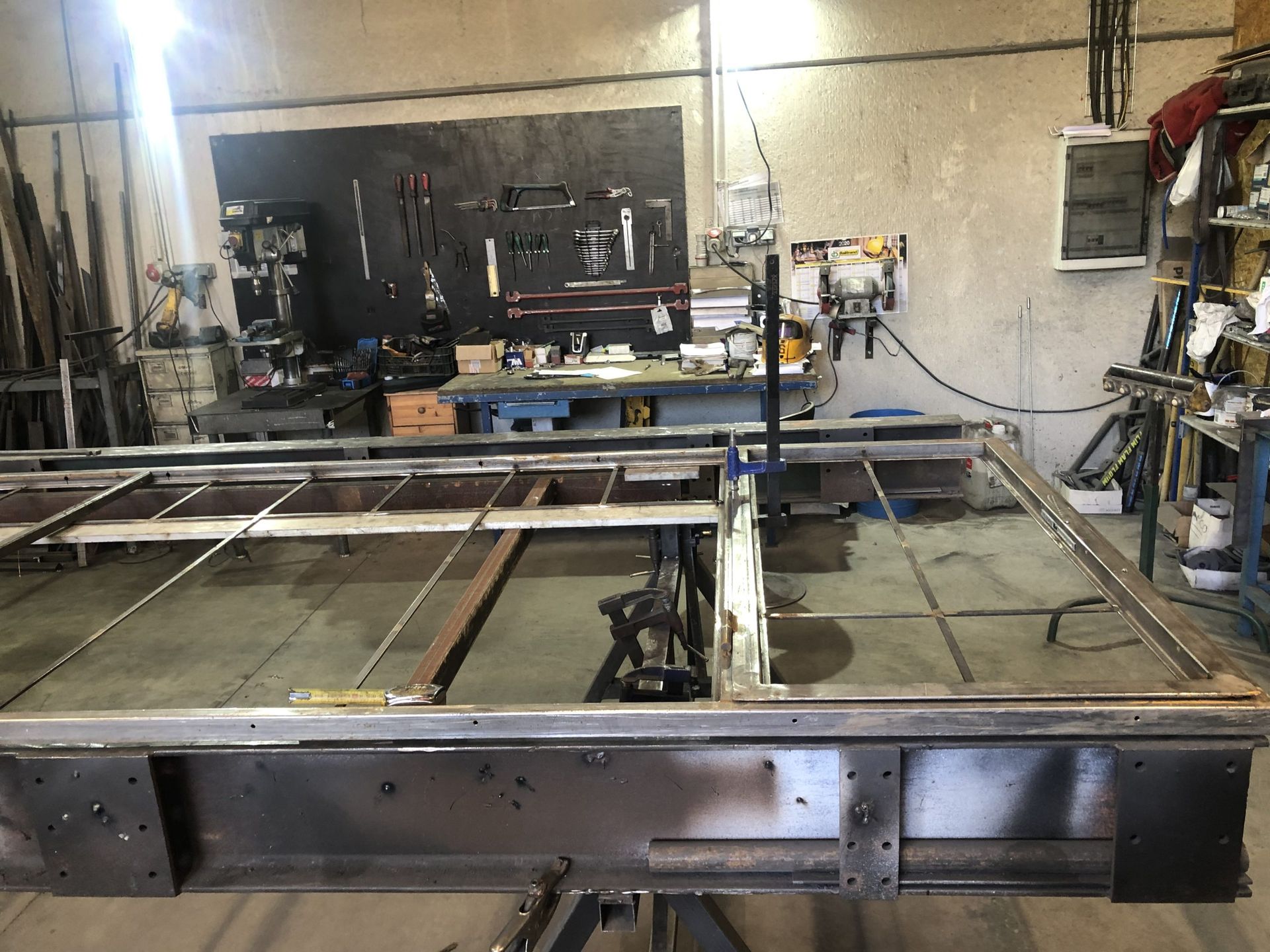 Atelier industriel avec une grande table à structure métallique et des outils en arrière-plan
