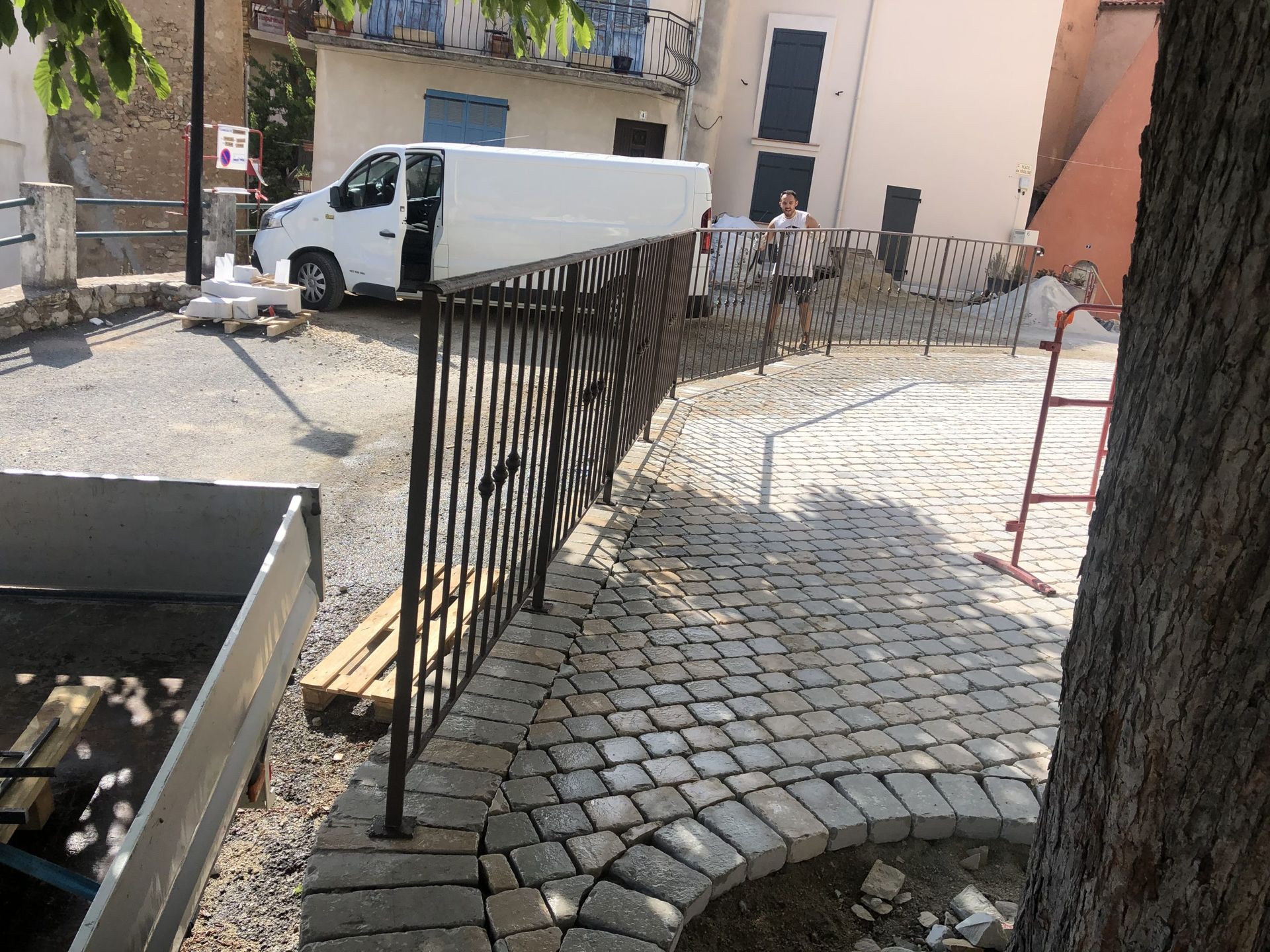 Allée en pierre avec rambarde noire longeant une camionnette blanche et la cour d'un immeuble