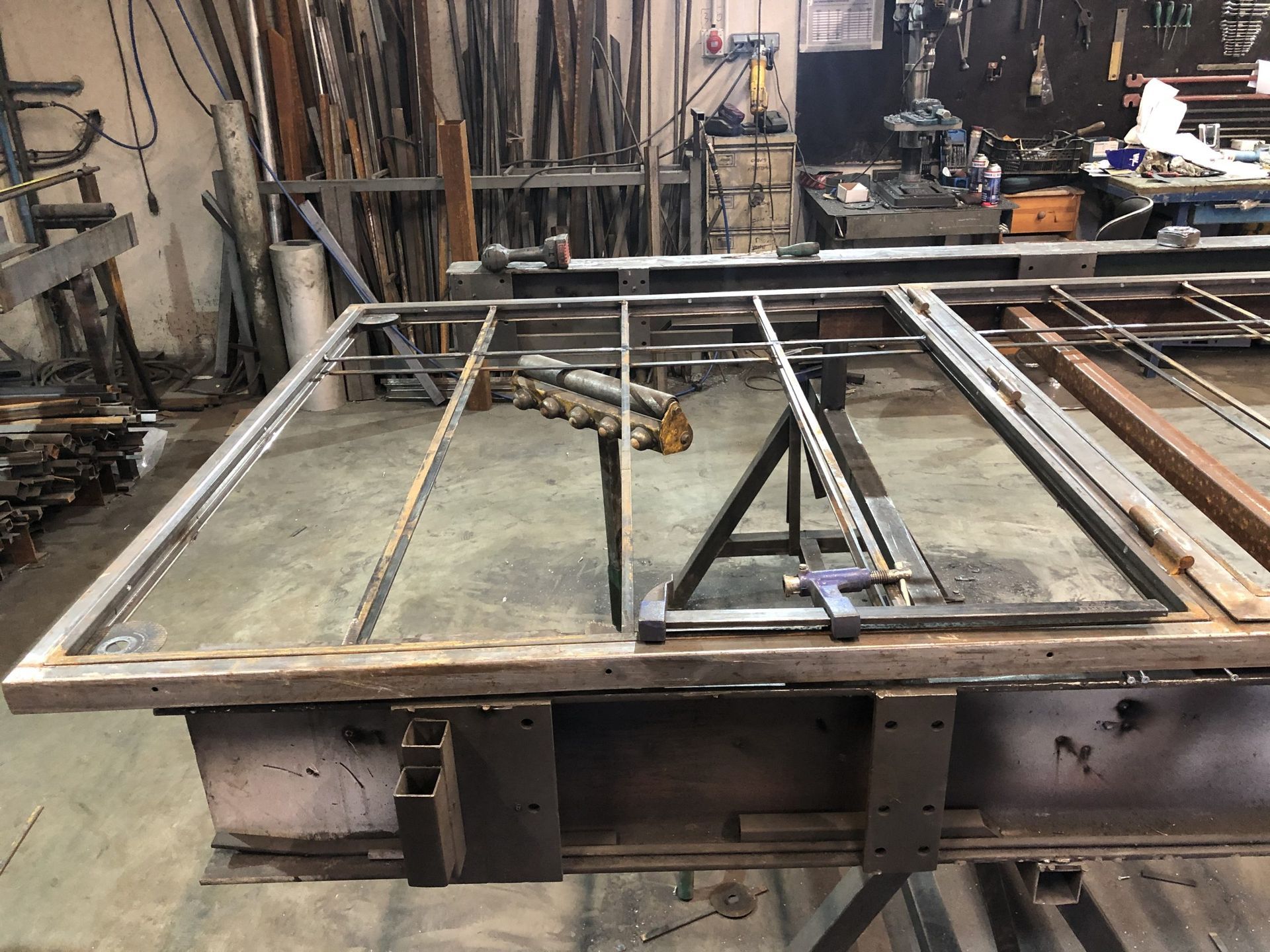 Assemblage d'une structure métallique dans un atelier, sur un grand établi, avec des outils et des matériaux en arrière-plan.