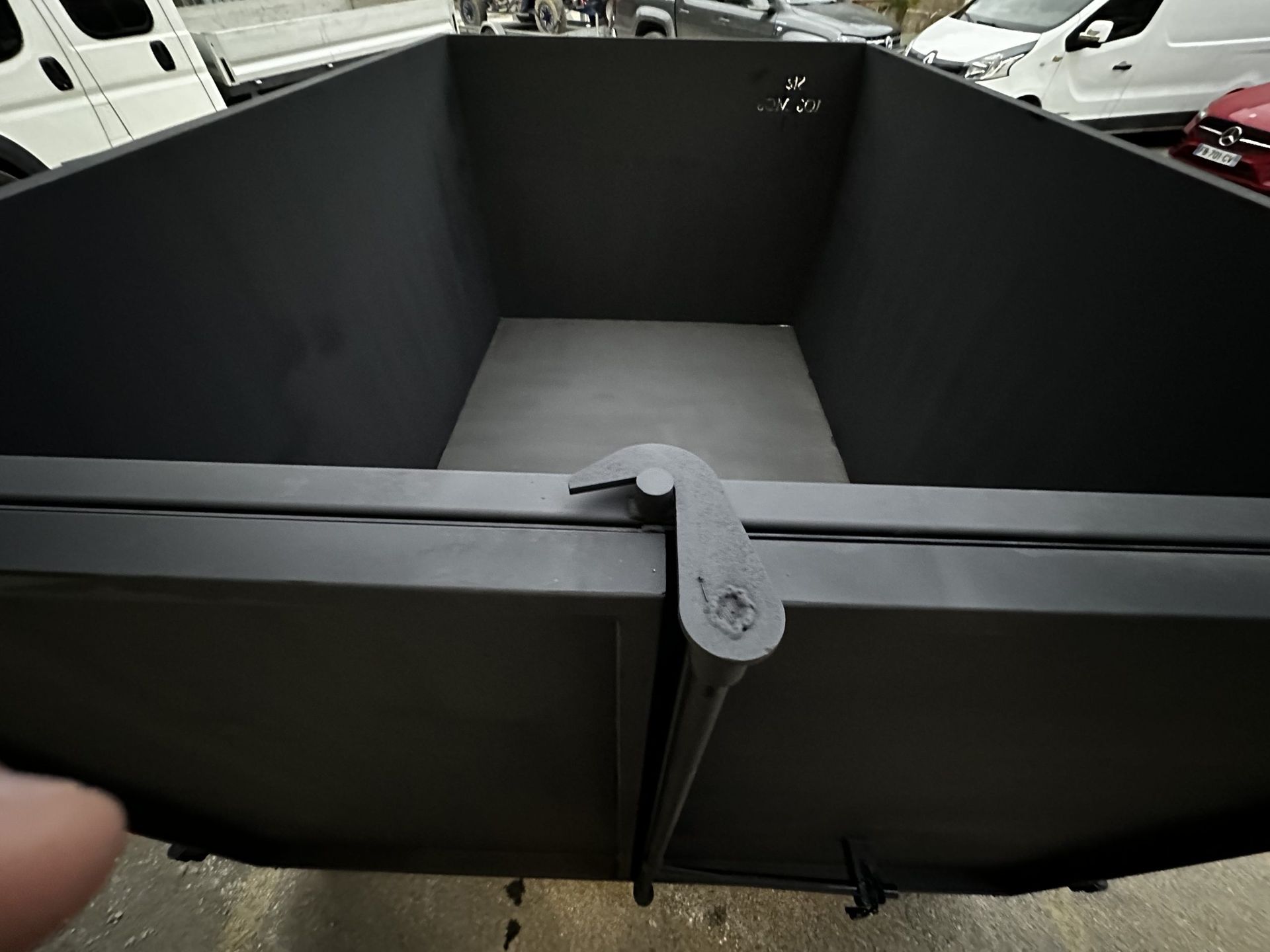 Séparateur ou barrière en tissu noir formant un enclos dans un parking, vu du ciel, avec des voitures en arrière-plan.