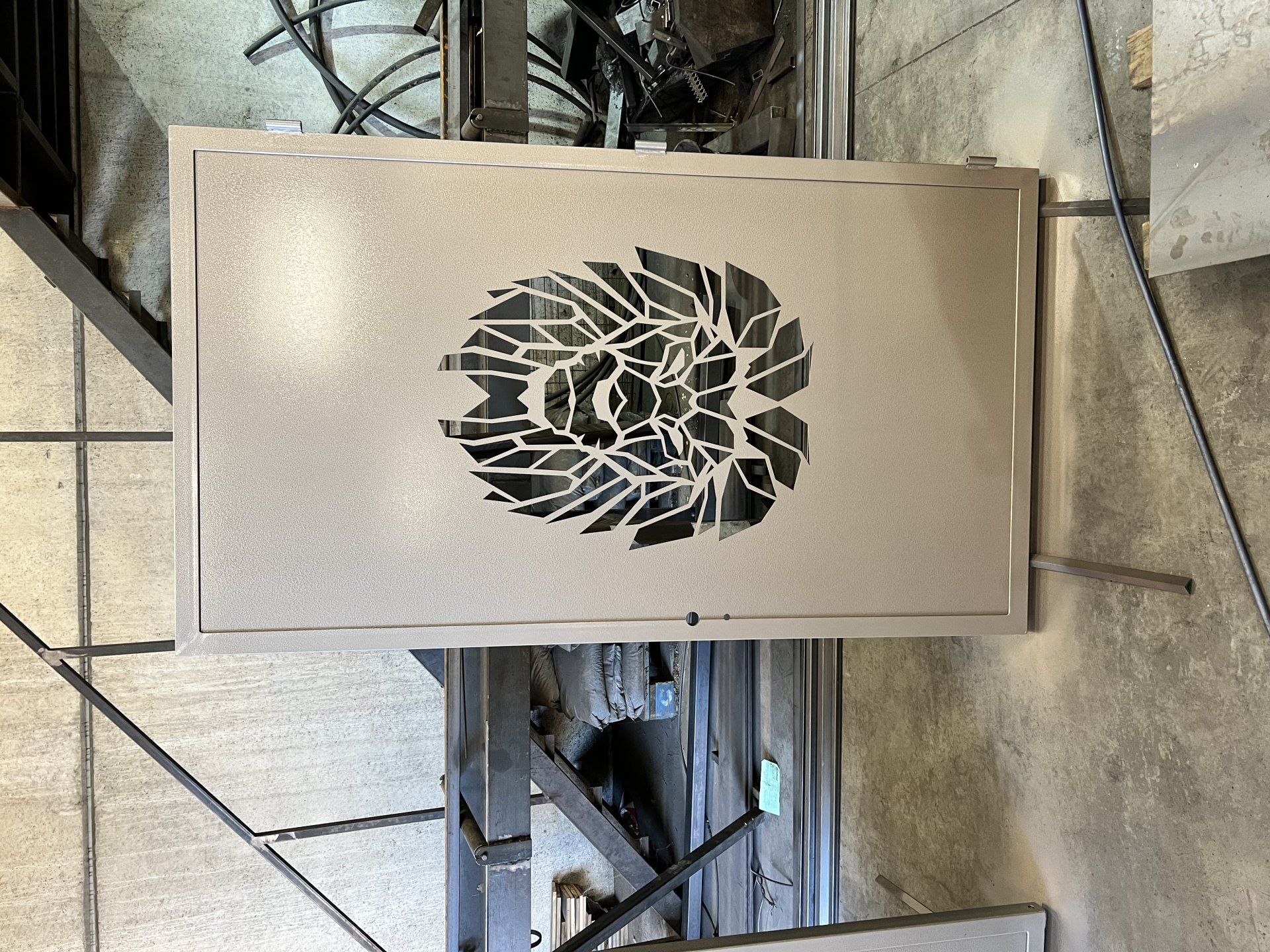Boîte métallique beige avec un logo en forme de feuille noire sur le dessus, fixée sur une surface industrielle.
