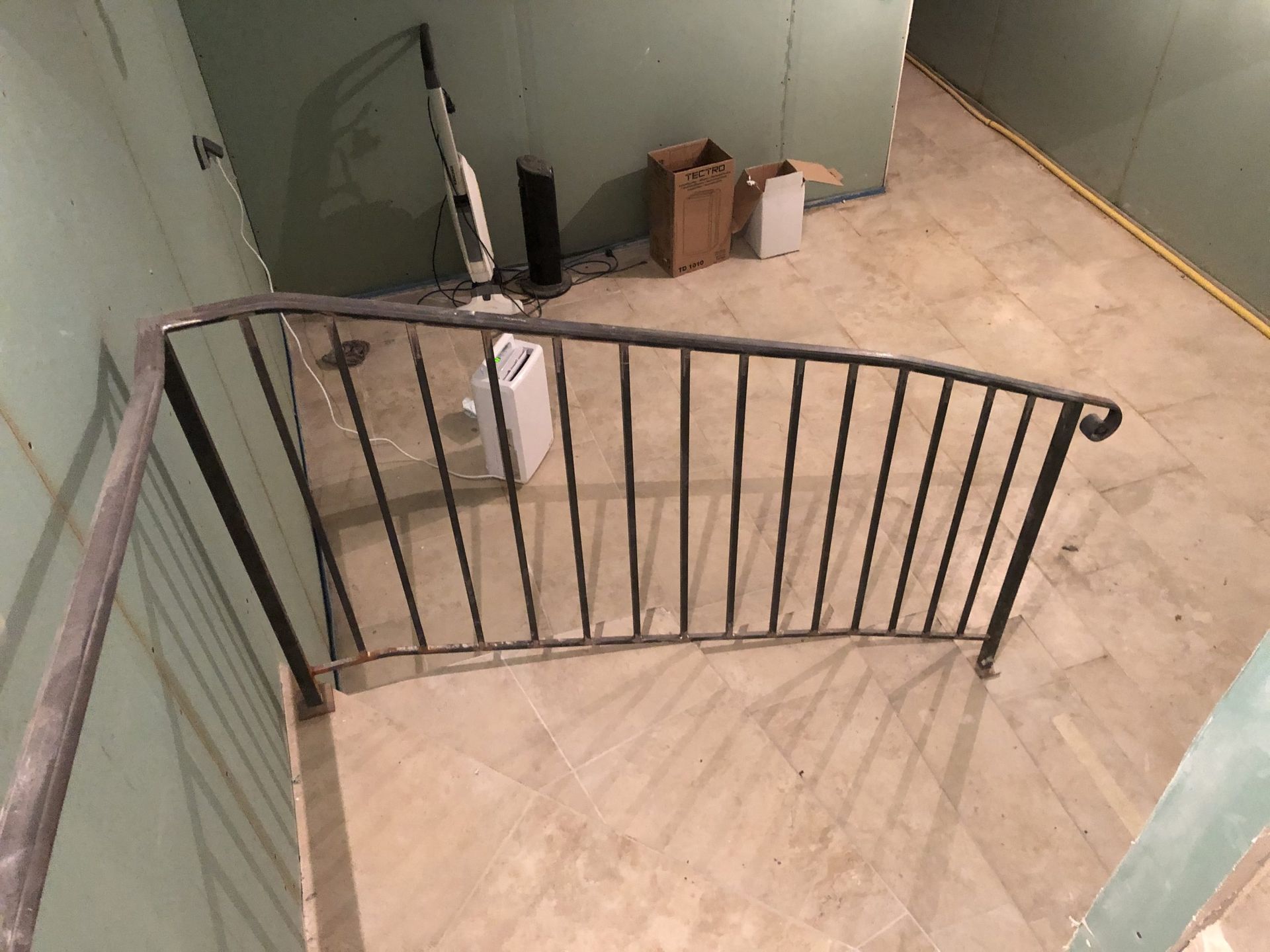 Rambarde incurvée en métal noir en haut d'un escalier recouvert de moquette dans un couloir