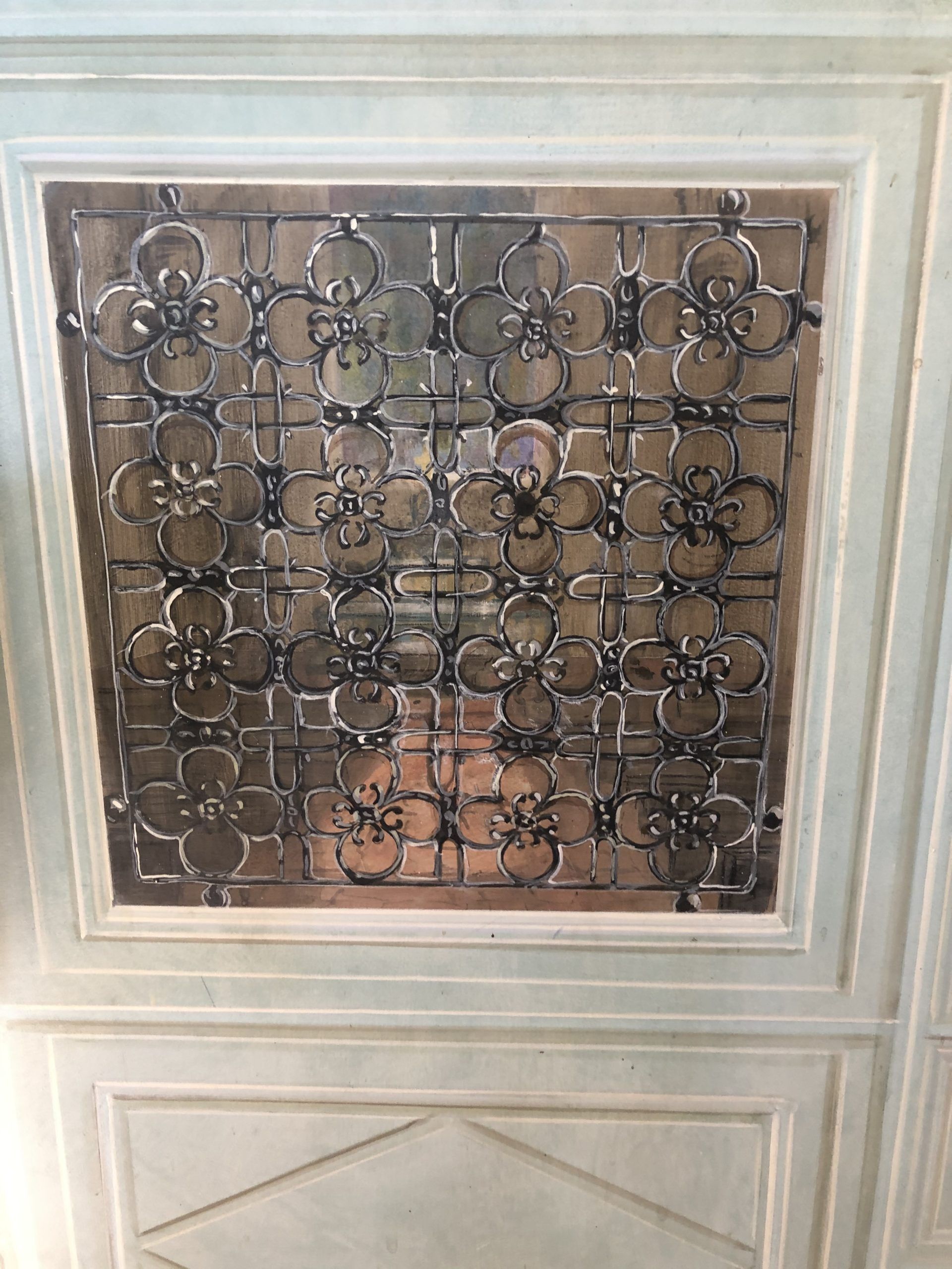 Grille décorative en métal noir au-dessus d'une fenêtre ou d'une porte encastrée dans un mur à panneaux blancs