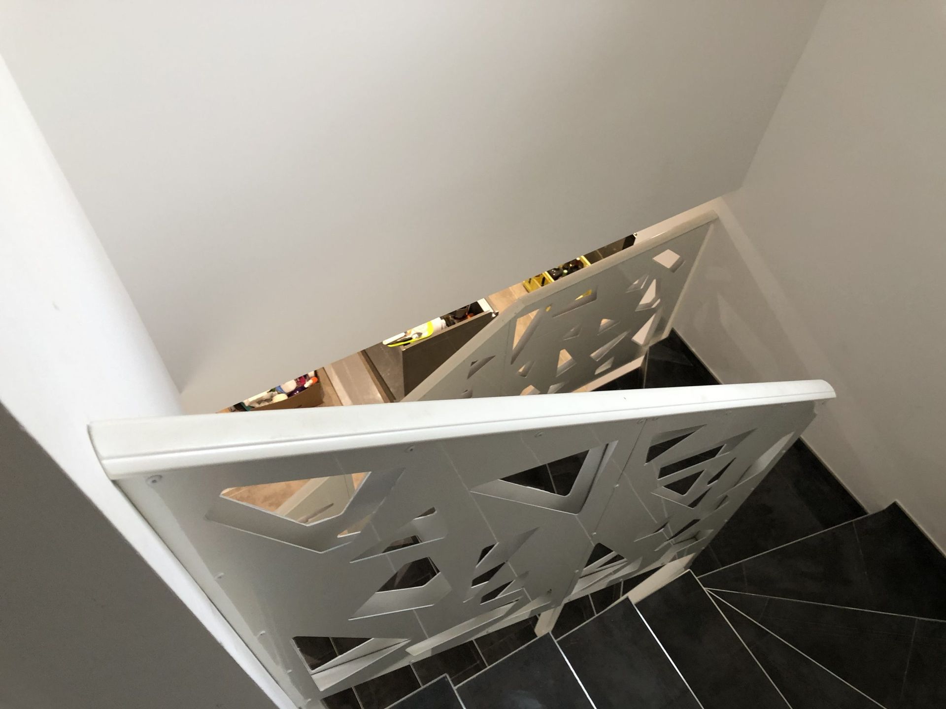 Rambarde d'escalier en treillis blanc à côté d'un escalier noir dans un espace intérieur étroit