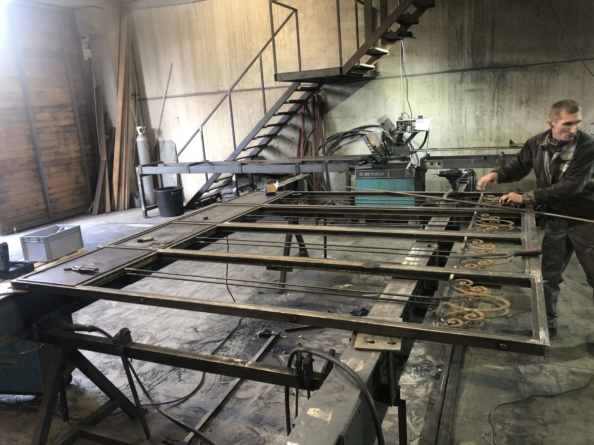 Ouvrier près de grandes structures métalliques dans un atelier industriel sombre