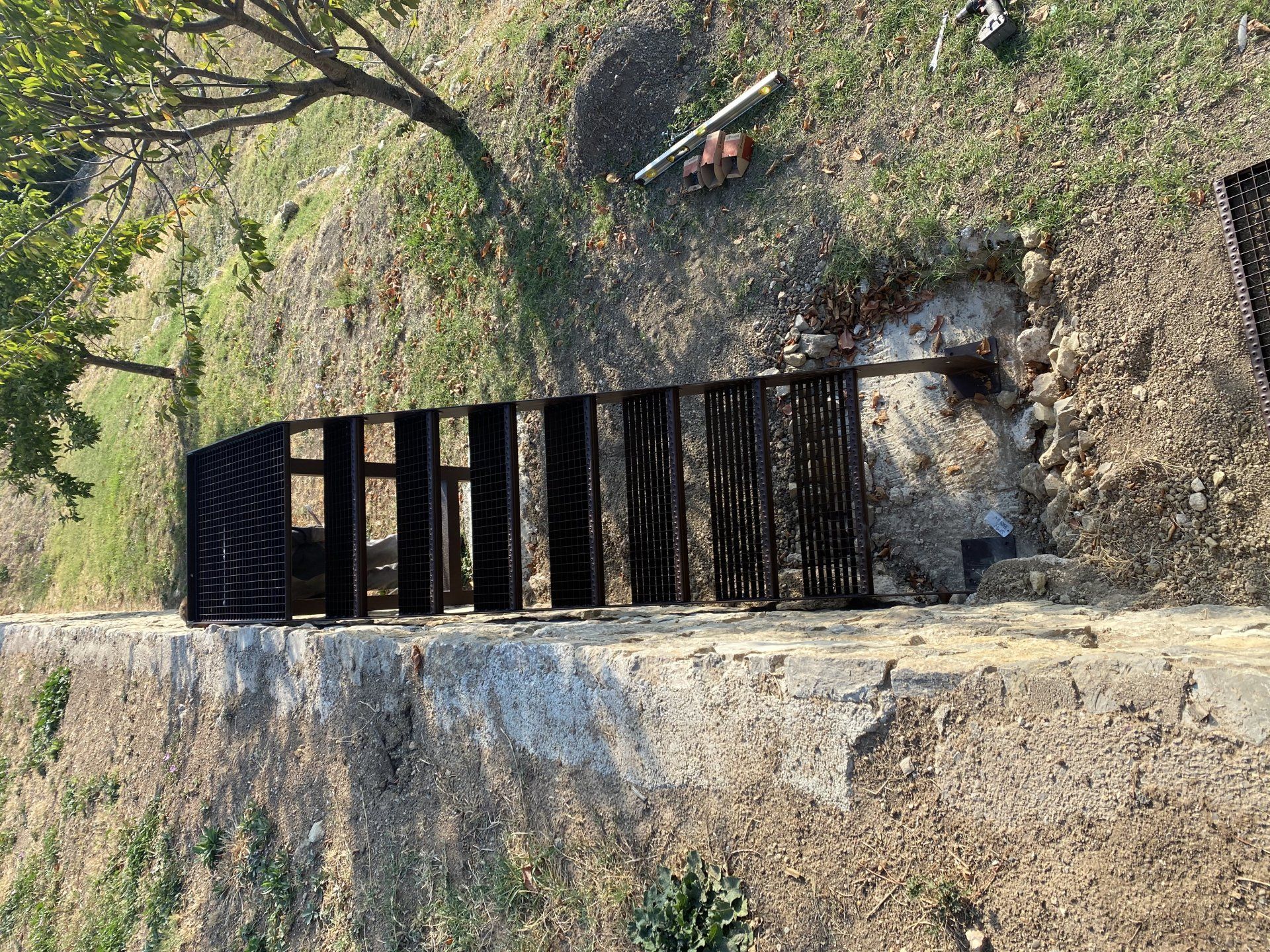 Escalier métallique abrupt descendant une falaise rocheuse au milieu des arbres et des feuilles mortes