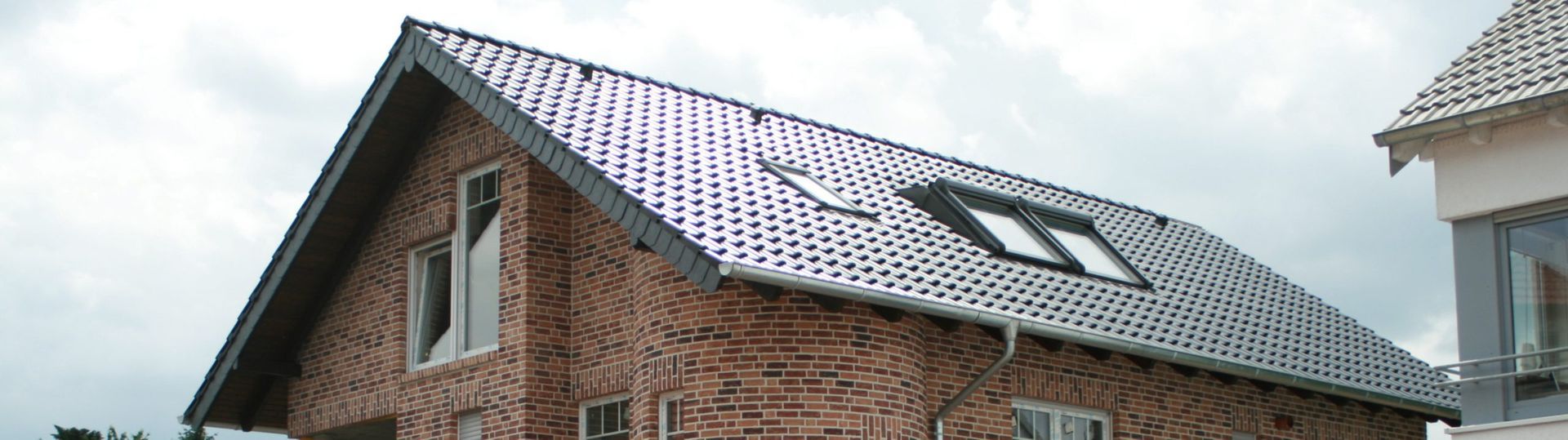 Zweistöckiges Backsteinhaus mit Satteldach und zwei Dachfenstern, teilweise sichtbares Nachbarhaus rechts