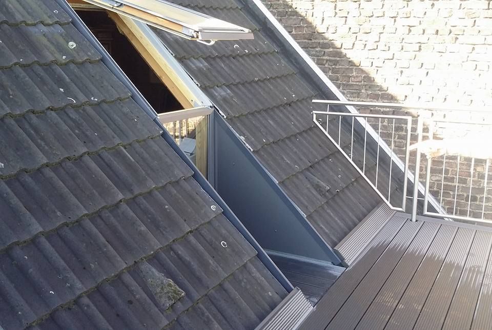 Dachterrasse mit Holzbelag, Dachfenster und schwarzem Ziegeldach mit offenem Fenster