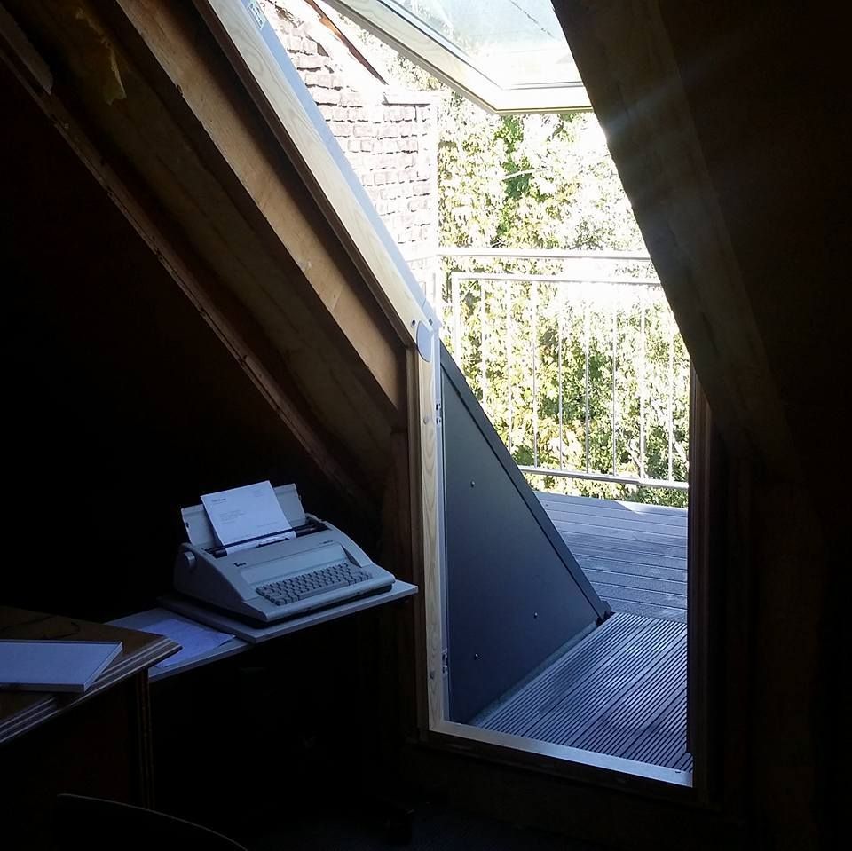Geöffnete Dachfenstertür mit Blick auf Holzterrasse und Balkon mit Metallgeländer