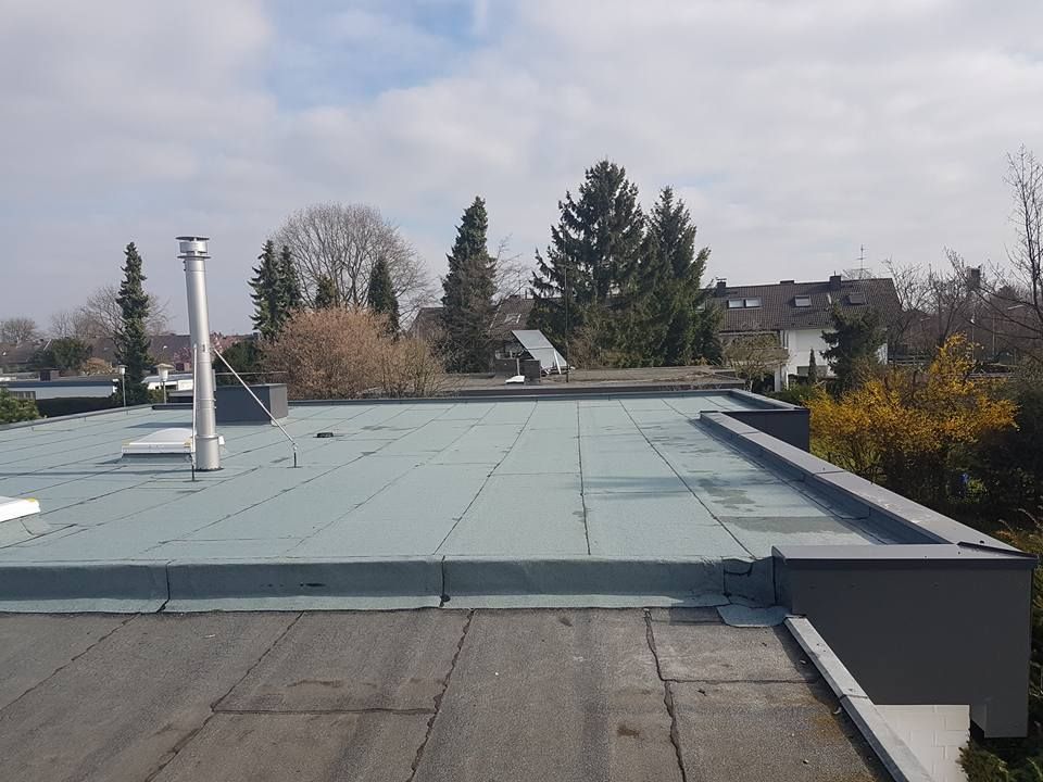 Flachdach mit grauer Dachabdichtung, Schornstein und umlaufender Dachkante