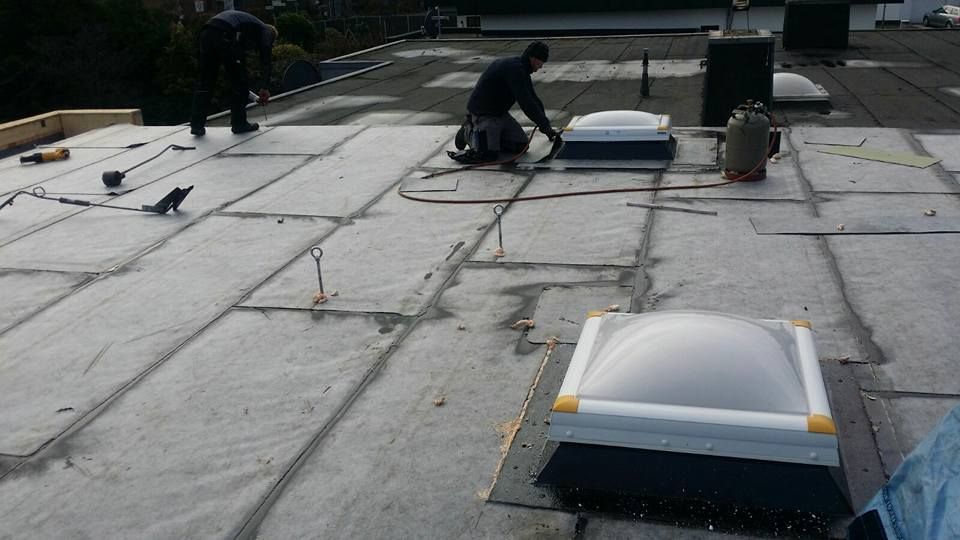 Dachdecker führen Abdichtungsarbeiten auf einem Flachdach durch.