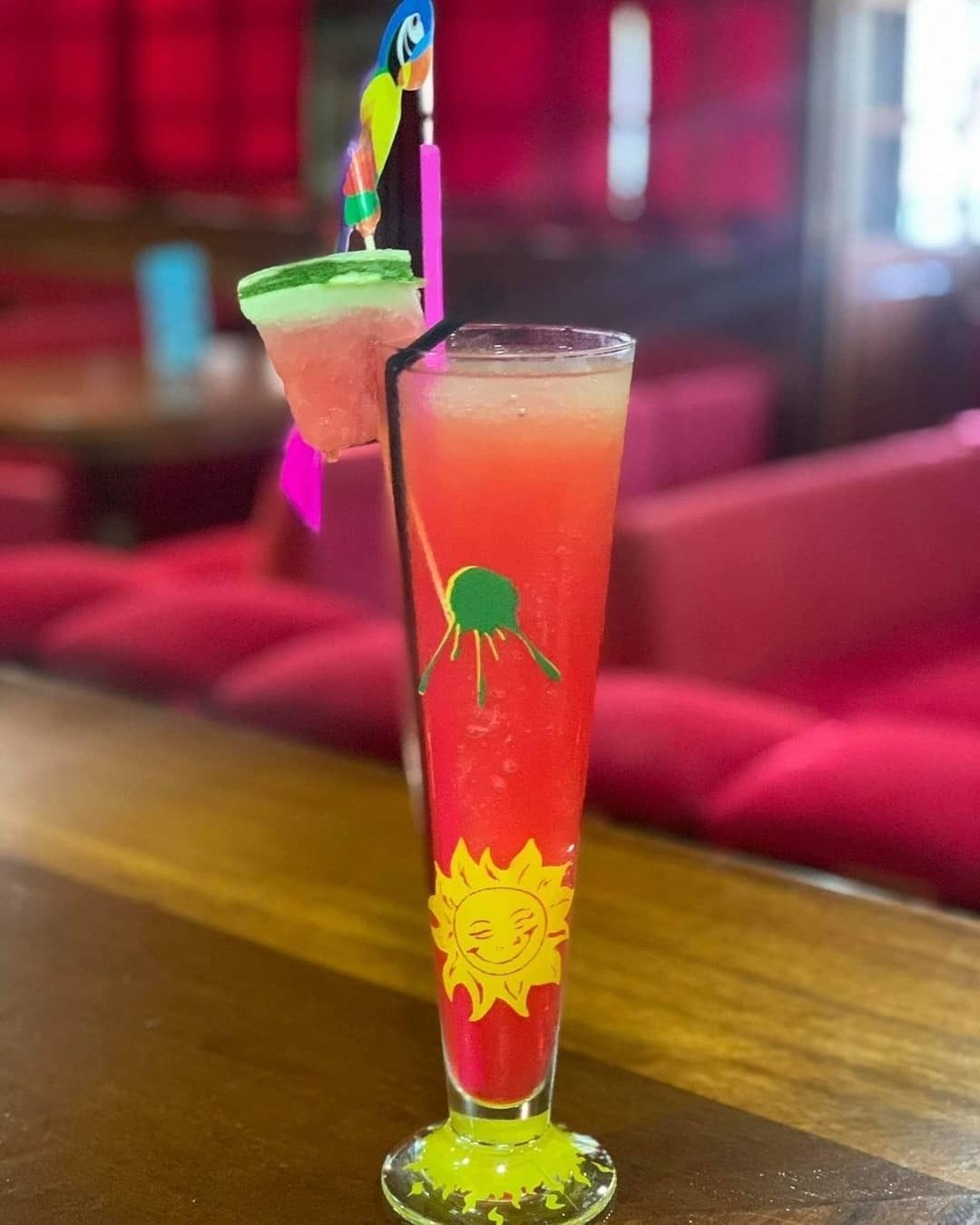 Una bebida roja en un vaso alto en una barra.