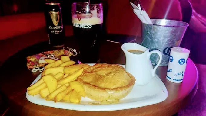 Un plato de comida con un pastel y papas fritas en una mesa.