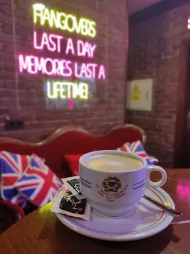 Una taza de café en un platillo frente a un letrero de neón