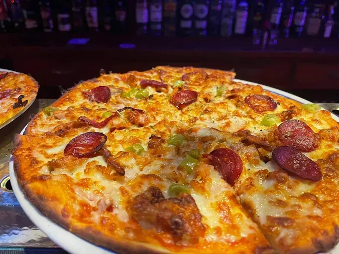 Una pizza con una rebanada quitada está en un plato sobre una mesa.