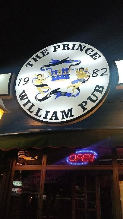 Un cartel del pub Prince William está iluminado por la noche.
