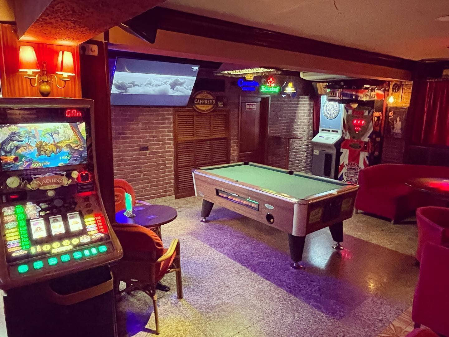 Hay una mesa de billar y una máquina tragamonedas en la habitación.