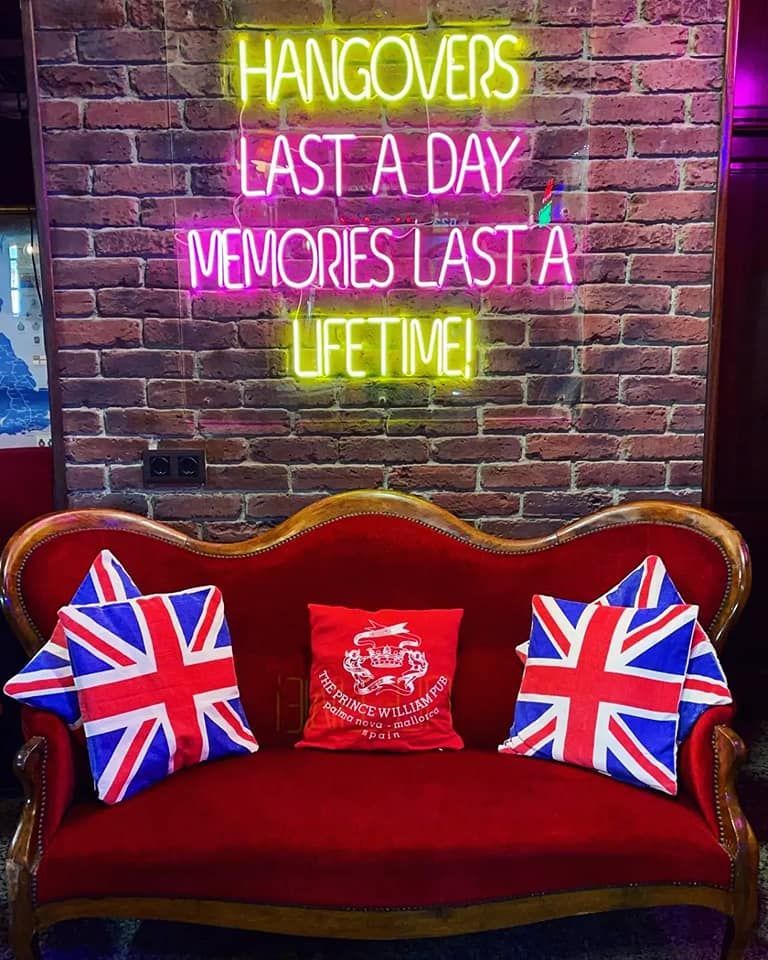 Un sofá rojo está sentado frente a un letrero de neón que dice: 